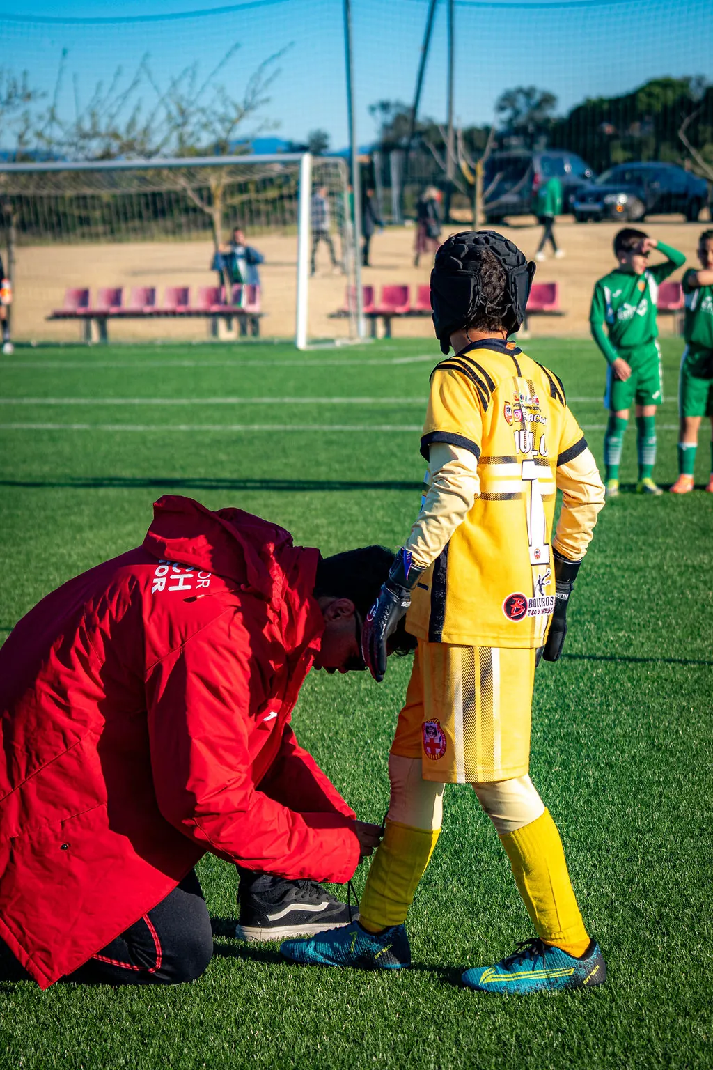 Membro da equipe BCN ajusta o uniforme de um pequeno goleiro antes do jogo