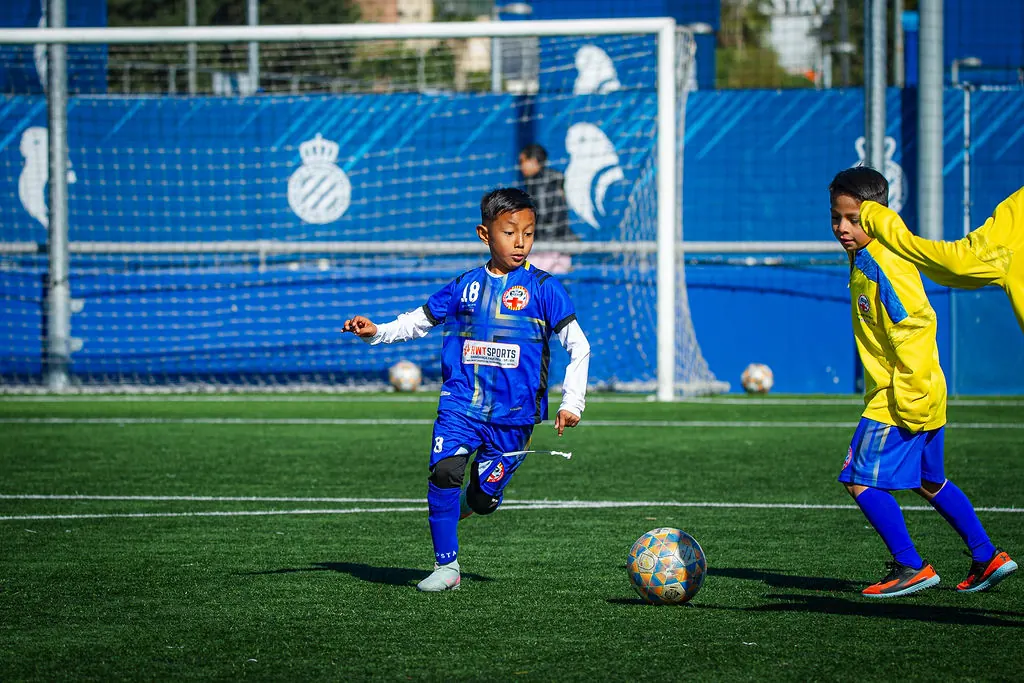 Jovem atleta conduz a bola em campo na Espanha